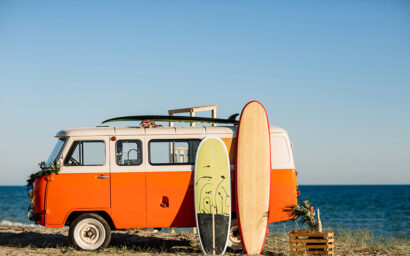 bus with a surfboard on the roof is a parked near the beach